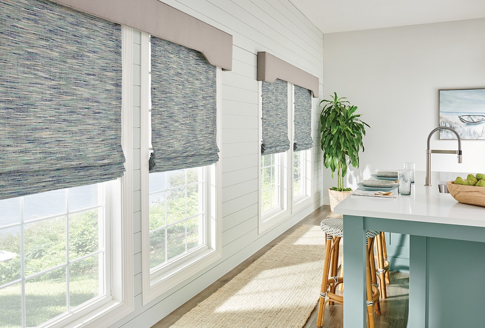 Roman shades filtering in light into a well designed kitchen.