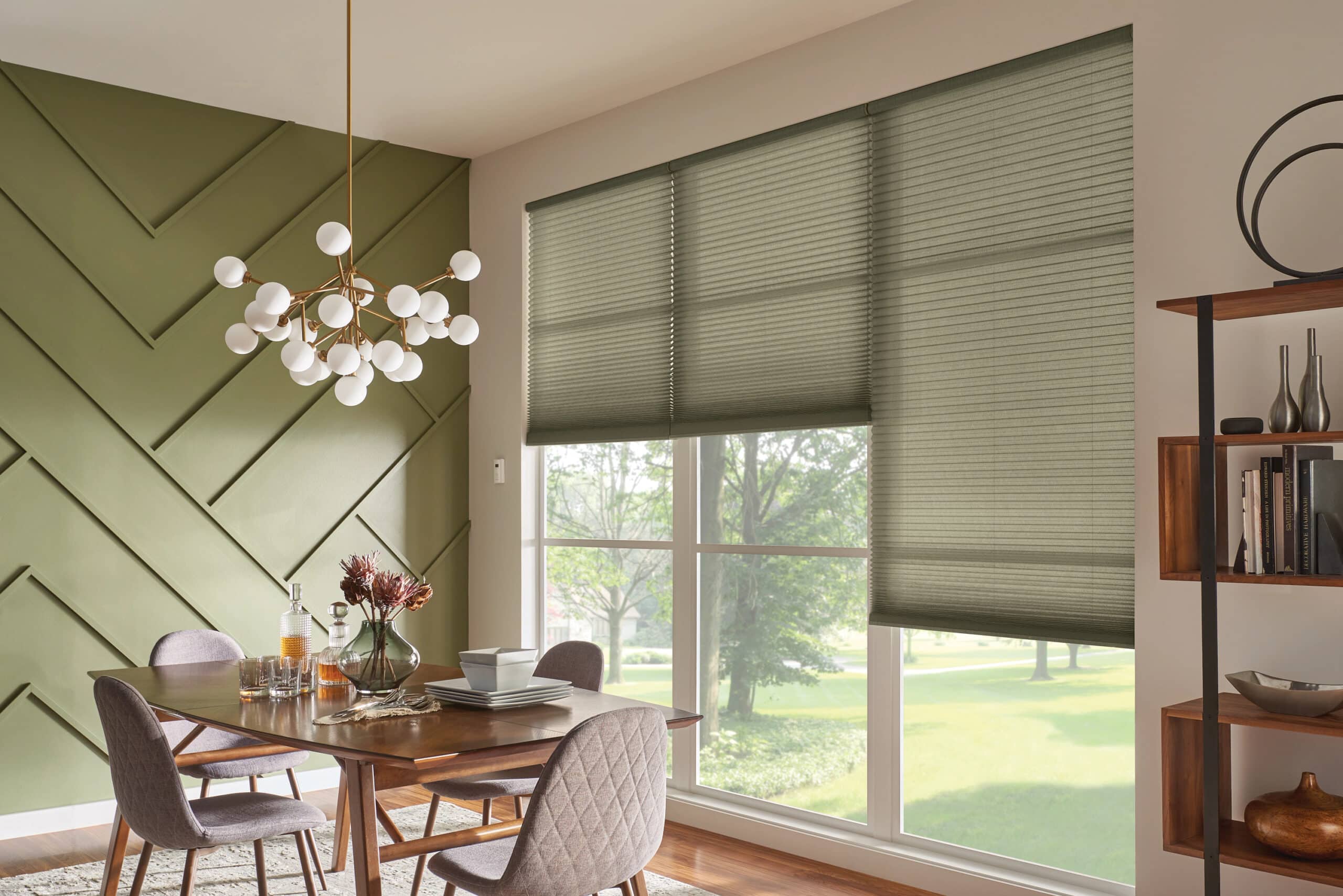 Olive green cellular shades filtering in light into a dining room. 