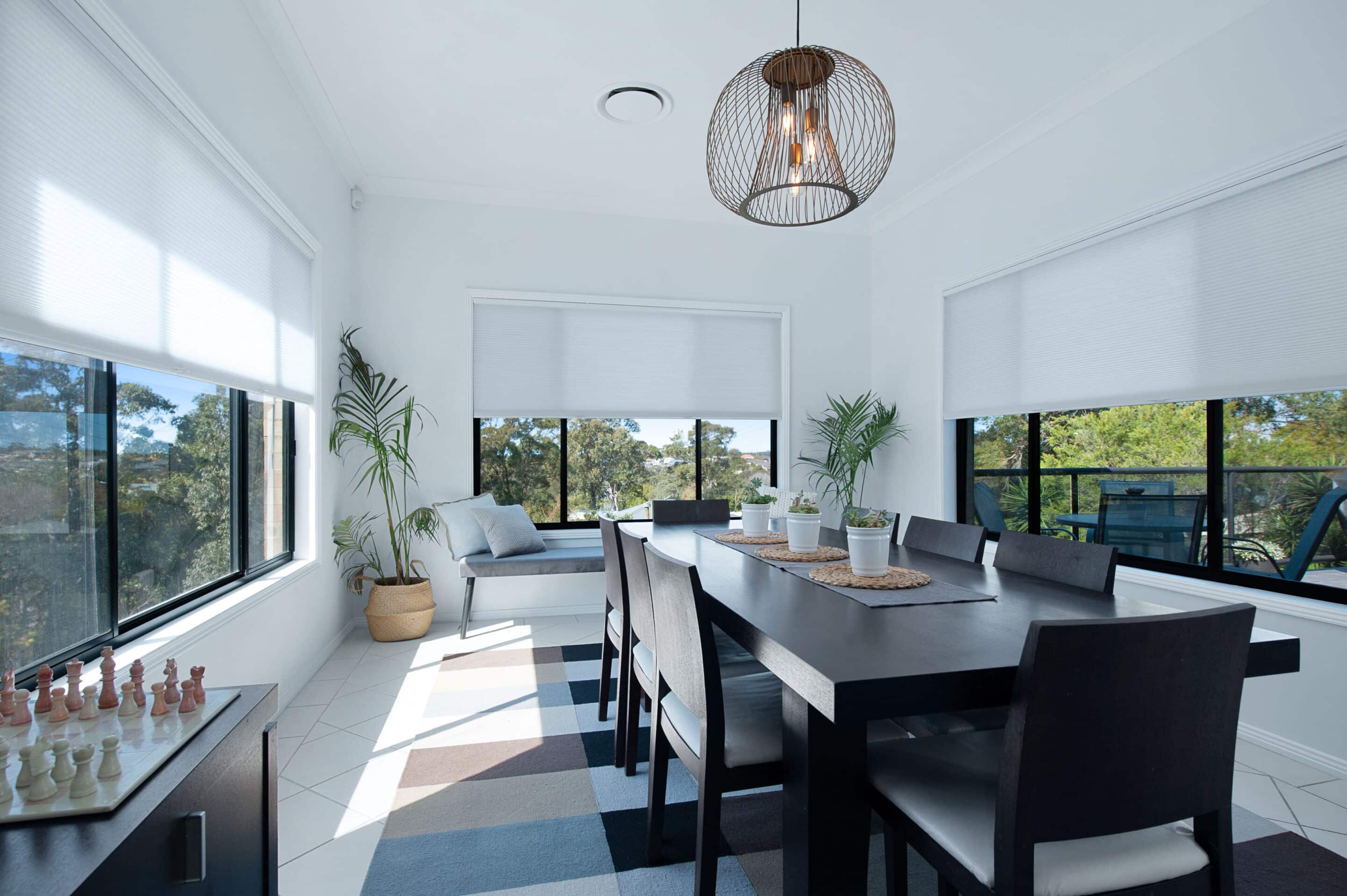 Sheer shades filtering in light into a dining room. 